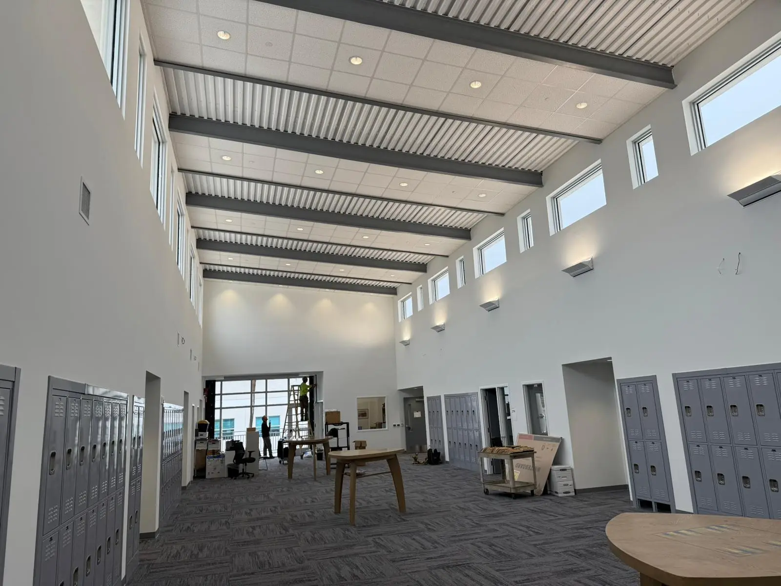 Large school interior showing steel beams, ceiling systems, windows, and installation work