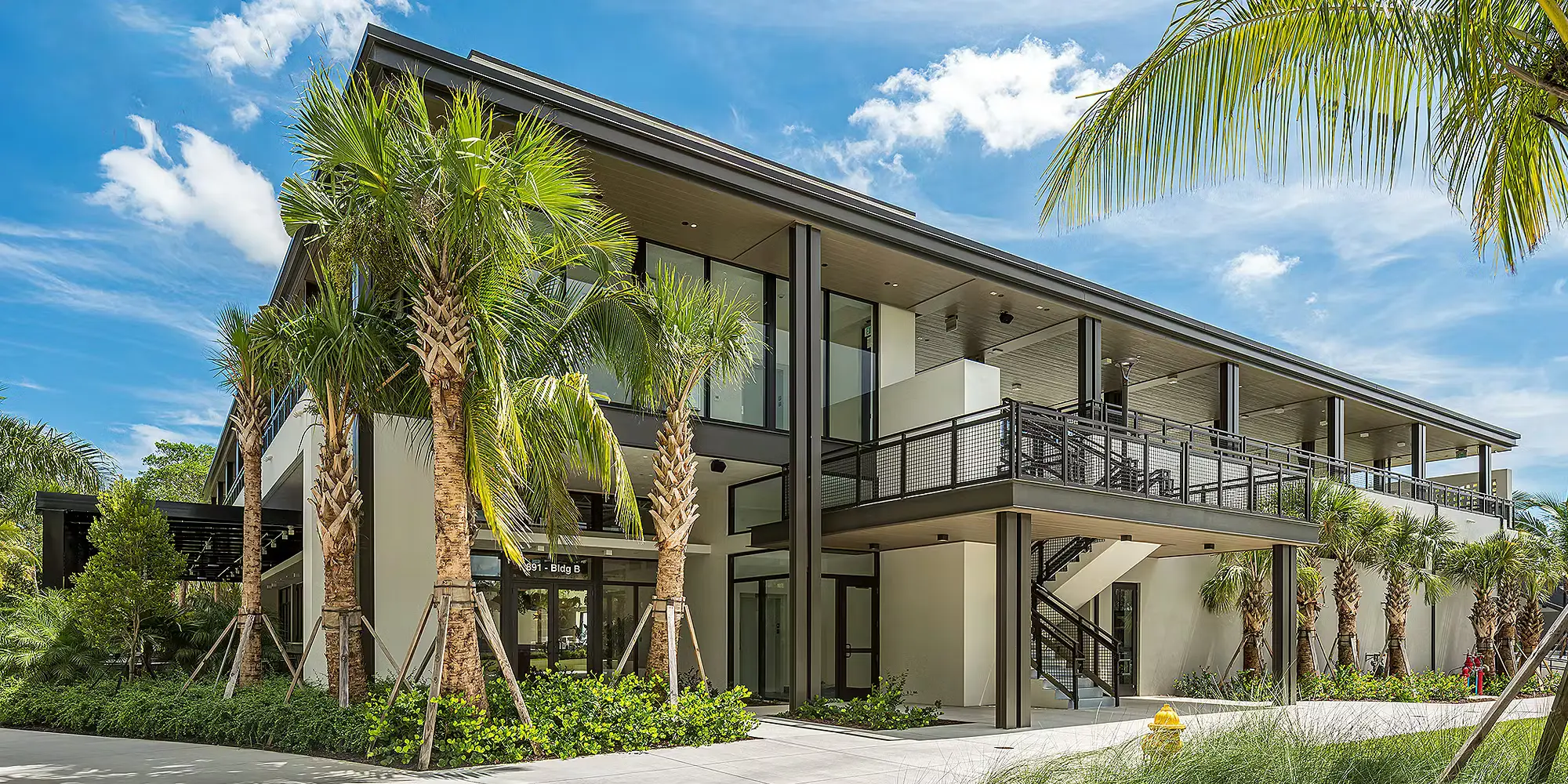 Exterior architecture, palm trees, and gathering spaces at The Fort Pickleball